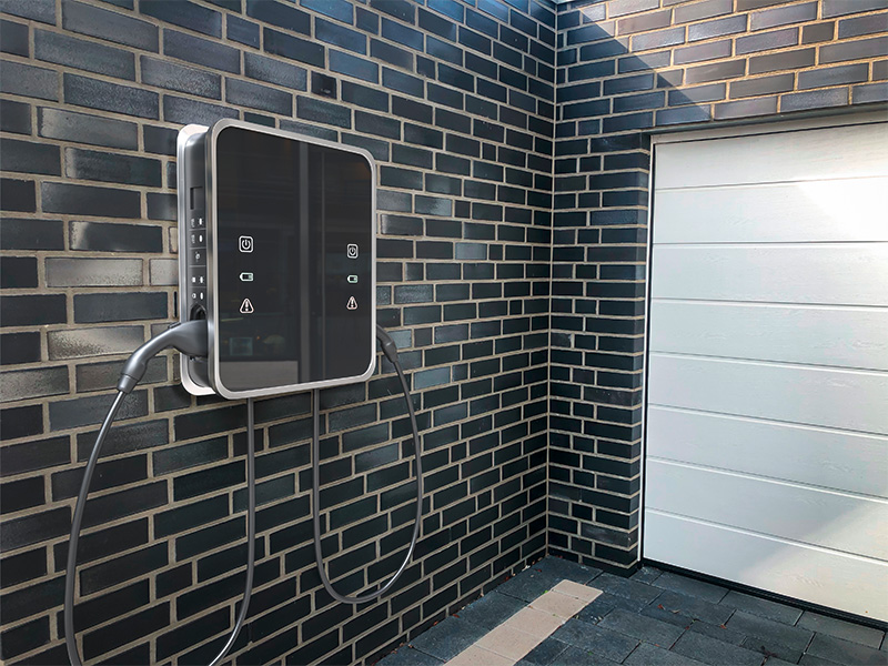 Elektroauto Ladestation an Garagen Hauswand mit angeschlossenem Ladekabel, zeigt moderne Ladeinfrastruktur für Elektromobilität bei Ford in Dortmund. 