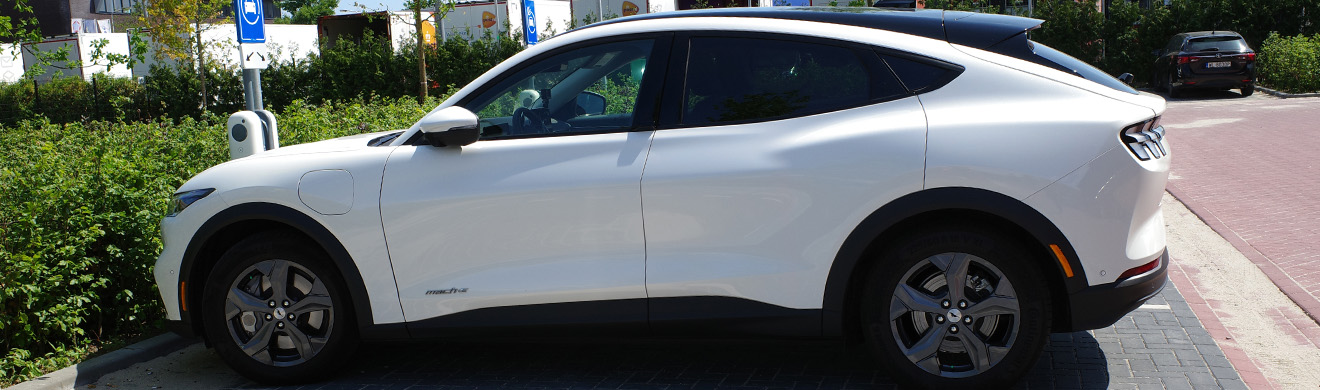 Weißer Ford Mustang Mach E beim Laden an einer öffentlichen E Ladesäule, modernes Elektrofahrzeug symbolisiert Elektromobilität bei Ford in Dortmund.