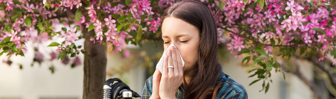 Frau niest aufgrund ihrer Frühlingspollenallergie