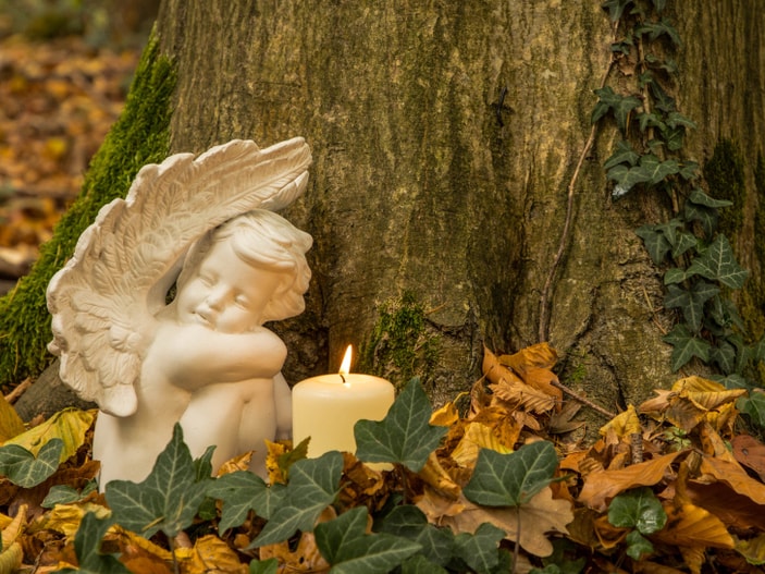 Engel mit Kerze auf einem Naturfriedhof