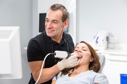 Zahnarzt, der die Zähne eines Patienten mit einem CEREC-Scanner scannt