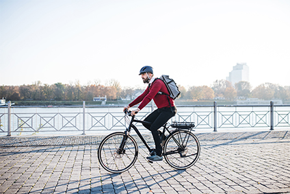 Moderner Businessmann fährt auf einem E-Bike durch die Stadt zur Arbeit.