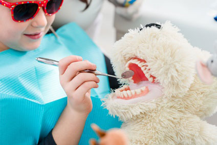 Child at dentist office looking after teeth of pet toy