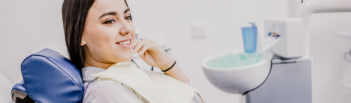Junge Frau besucht geduldig die Zahnarztpraxis. Schöne lächelnde Frau mit gesunden weißen Zähnen sitzt auf einem zahnmedizinischen Stuhl. Zahnarztklinik. Stromatologie