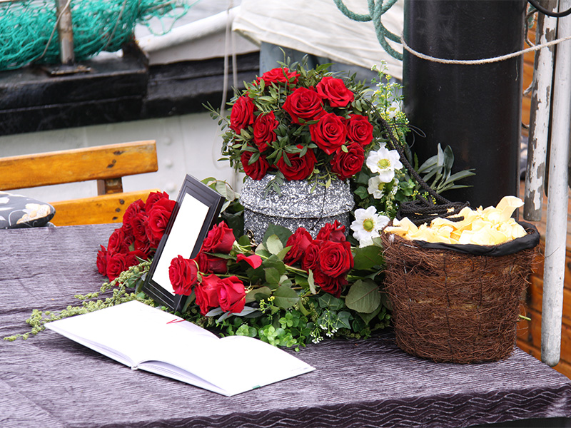 Schiff auf der Ostsee mit Urne und Blumenschmuck – würdiges Symbol für die Arbeit eines Seebestatters.