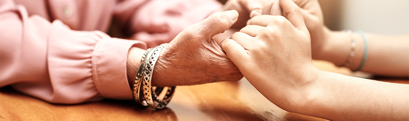 Zwei Personen halten einander die Hände in ruhiger Umgebung – symbolisiert einfühlsame Trauerbegleitung in Dortmund.