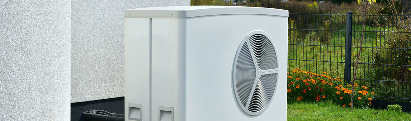 Moderne Luft-Wasser-Wärmepumpe vor neu gebautem Wohnhaus, energieeffiziente Heizlösung für nachhaltiges Wohnen in Dortmund und Umgebung.